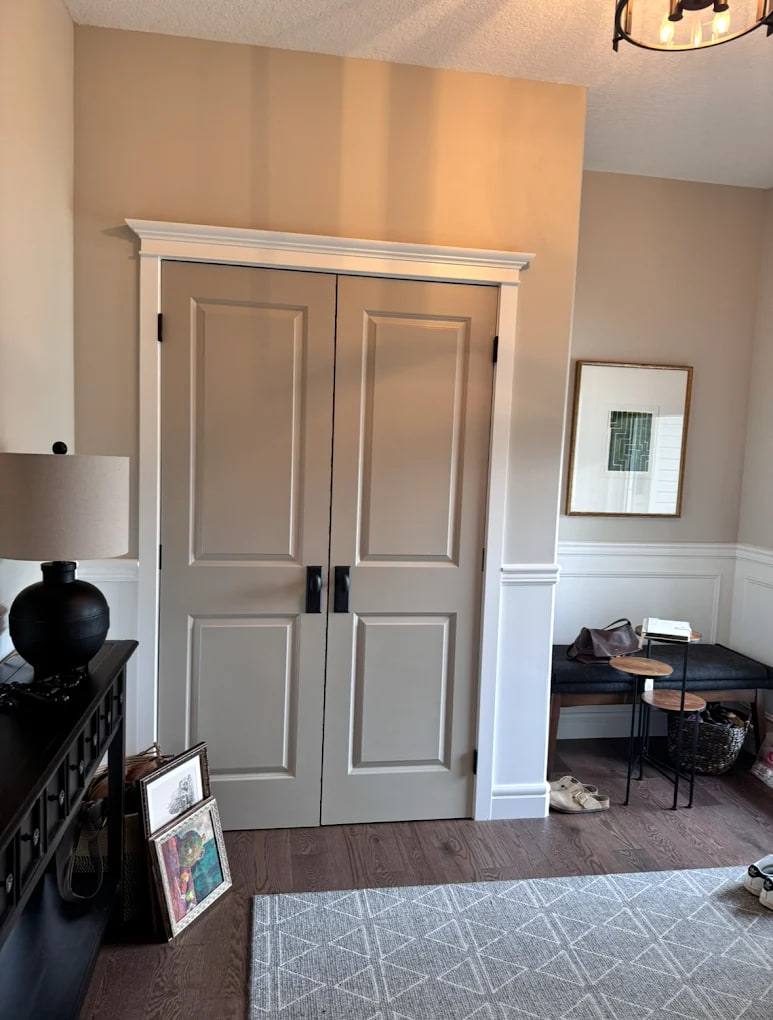 White double doors with a built-up header and casing, flanked by chair rail wainscoting