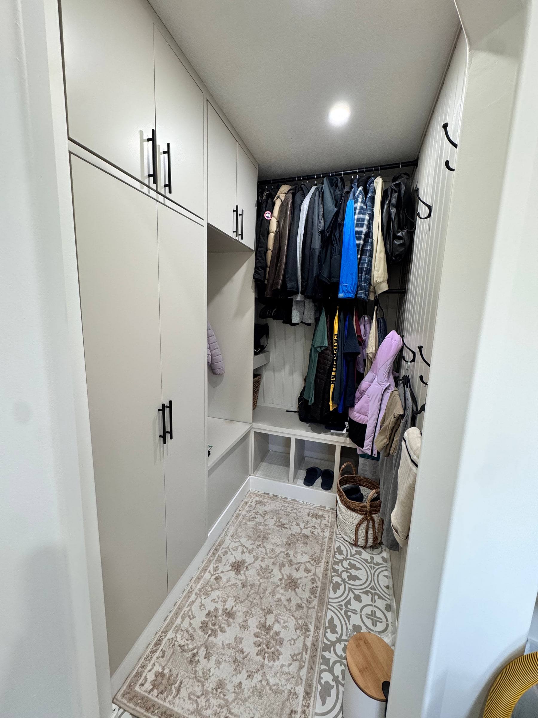 The same mudroom built-in in daily use with coats hanging in the open locker section