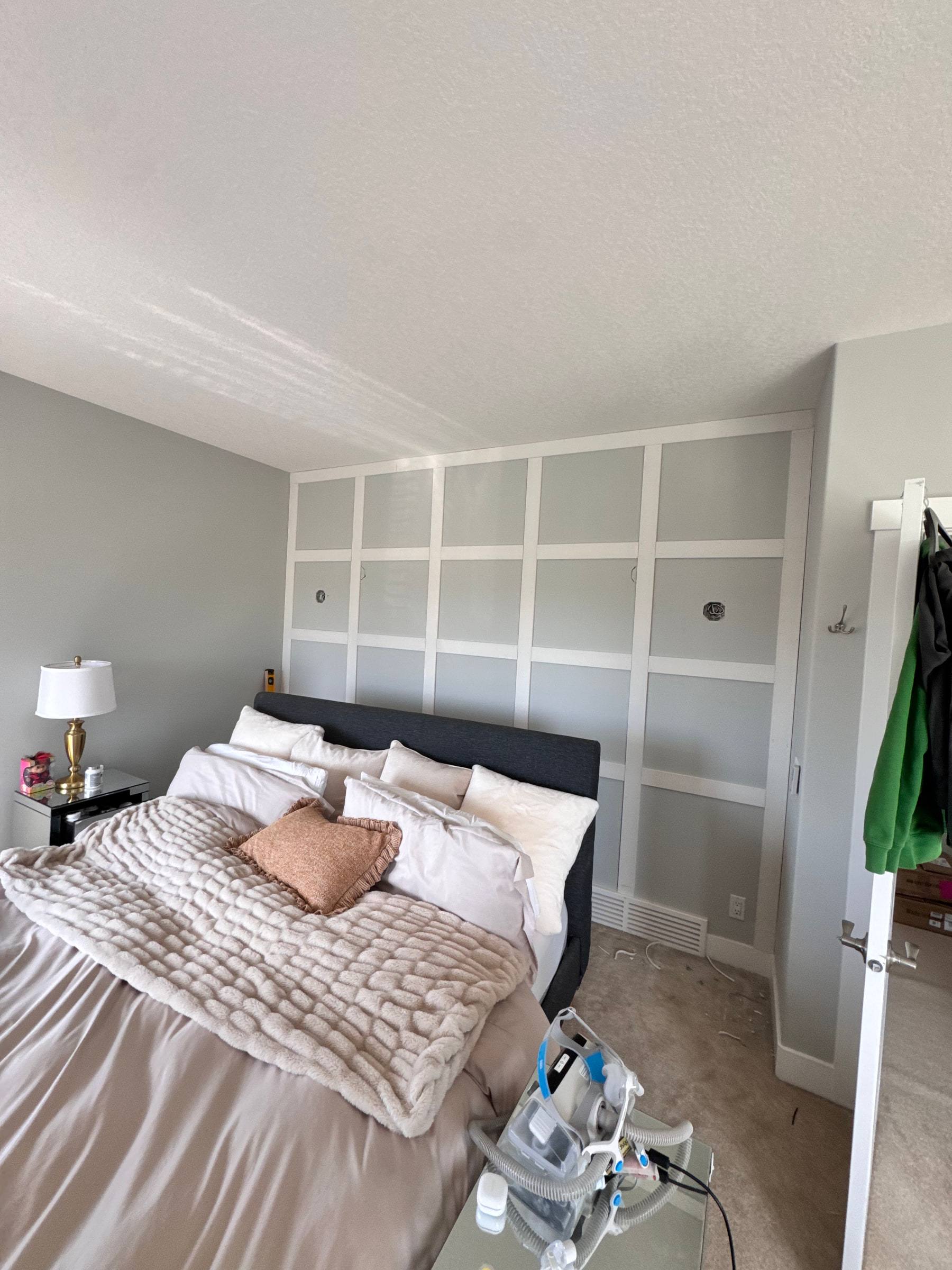 Bedroom with a grey square-grid board-and-batten feature wall behind the bed