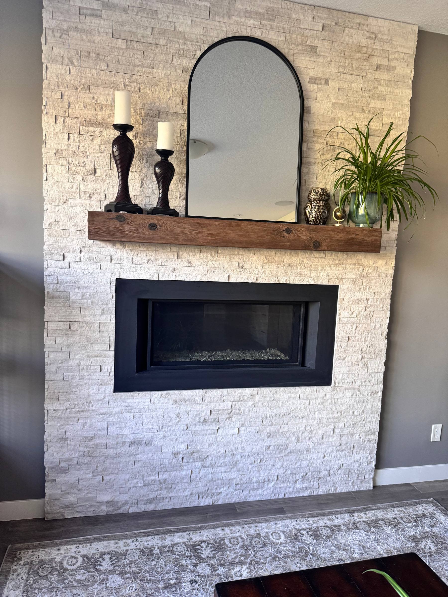 Floor-to-ceiling stacked stone fireplace surround with a rustic wood mantel