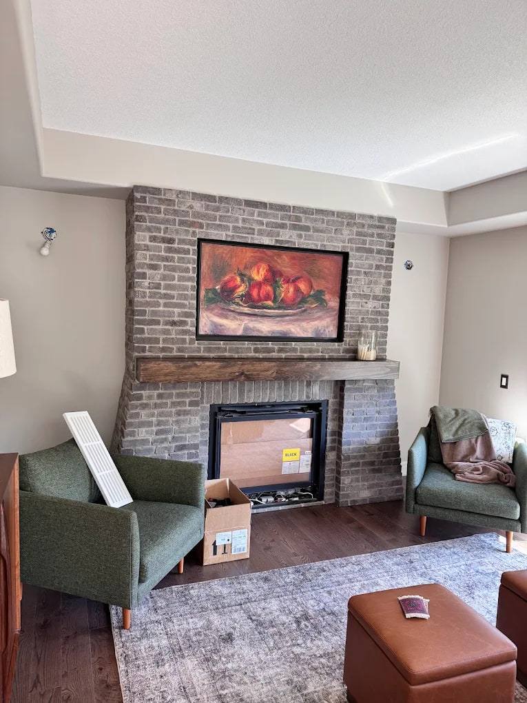 Grey brick fireplace with a rustic wood mantel in a finished living room
